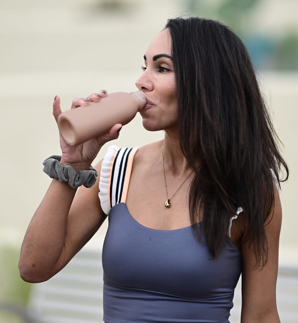 Woman drinking chocolate milk from a bottle.
