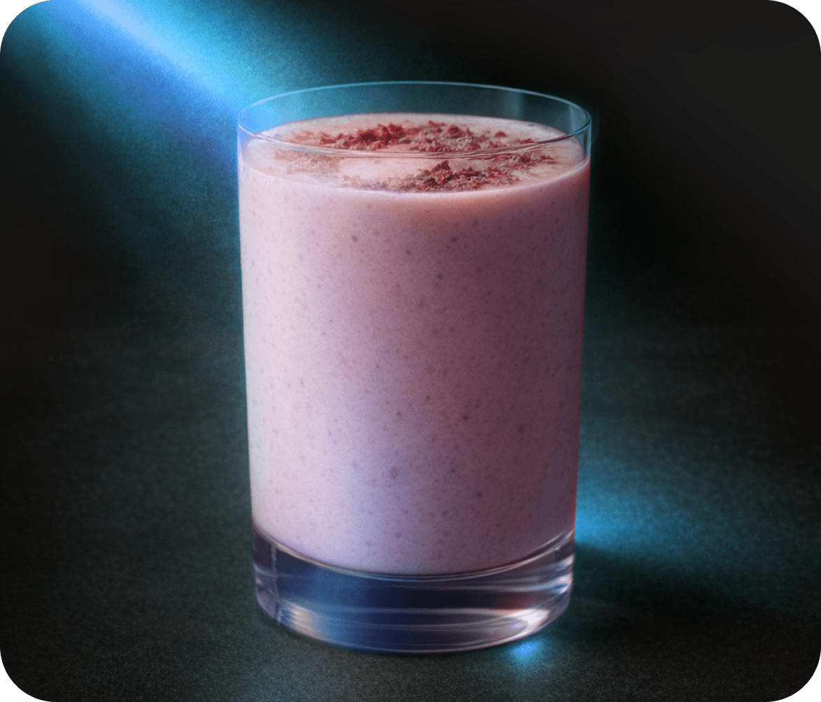 A glass of a pink strawberry moon milk smoothie. A blue beam of light strikes through the glass.